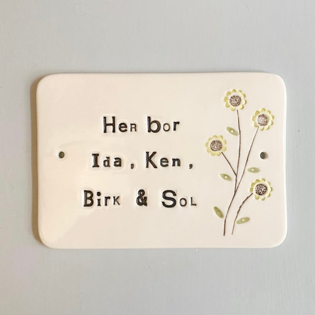 Dørskilt - med "her bor" og en blomst